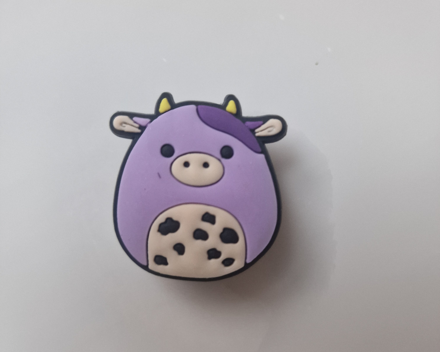 a purple cow with black spots on it's face